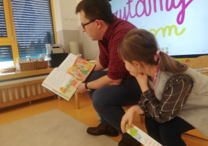 Gabrysia i jej tata pokazują ilustracje do bajki